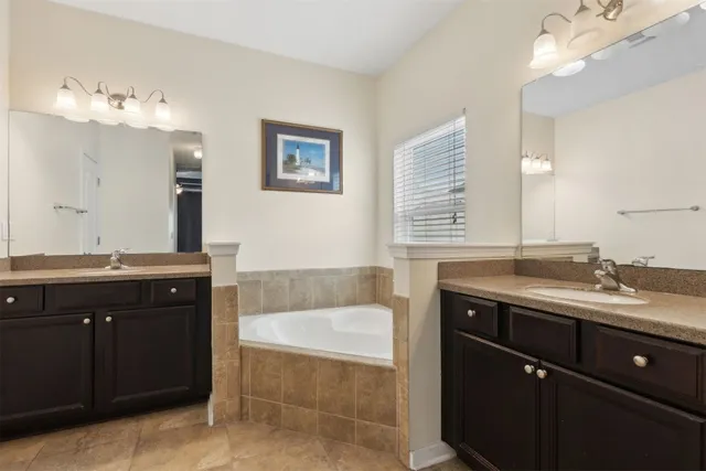 a bathroom with a tub double vanity sink and mirror