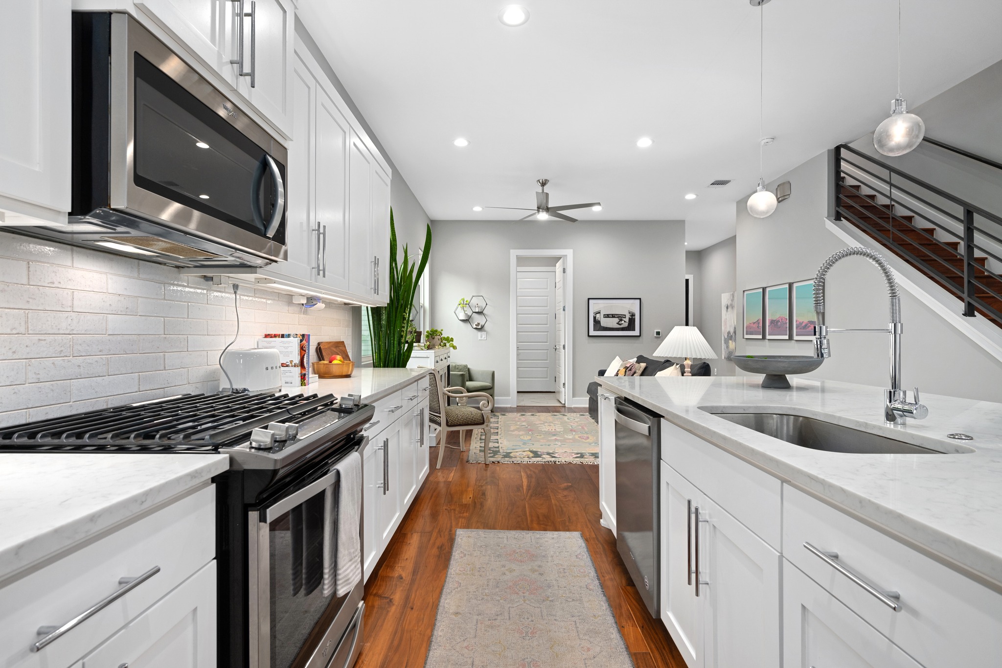 1103 Saucedo Street, Unit 1 Austin, TX 78721 - Photo 13 of 40 A well-appointed kitchen features stainless steel appliances, gleaming white cabinetry, and rich hardwood floors leading to an open-concept living area.