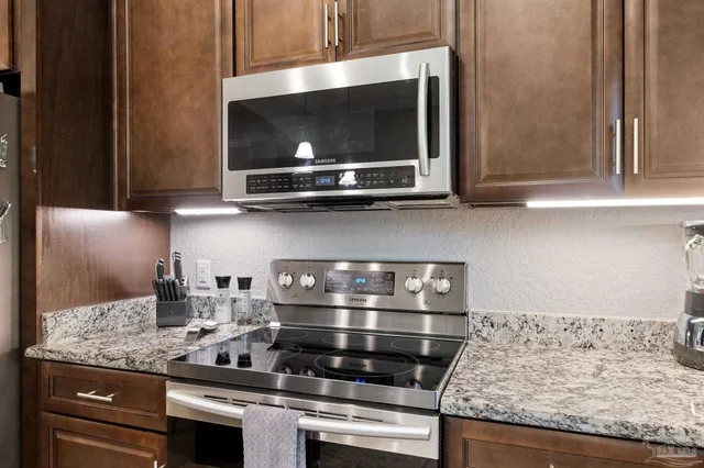 a kitchen with granite countertop a stove and a microwave