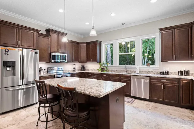 a kitchen with granite countertop a center island and stainless steel appliances