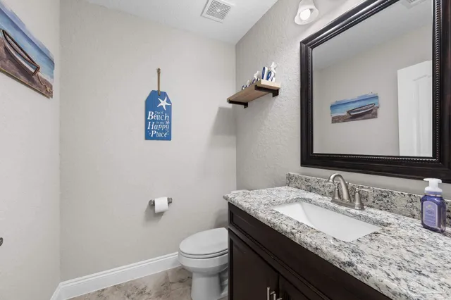 a bathroom with a granite countertop sink a toilet and a mirror