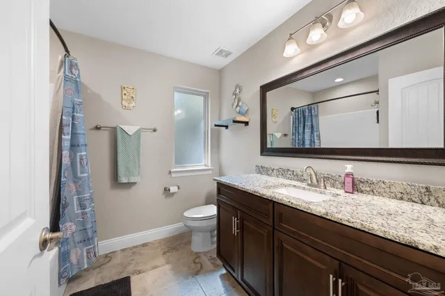 a bathroom with a granite countertop sink toilet and mirror