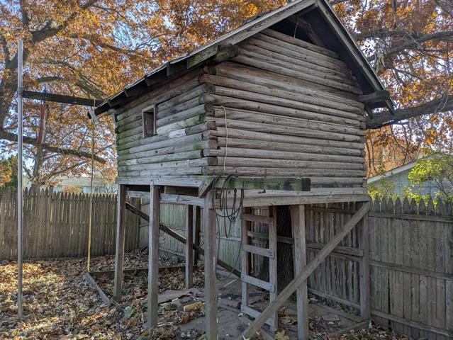 a view of a house with a tree bed chair and wooden fence