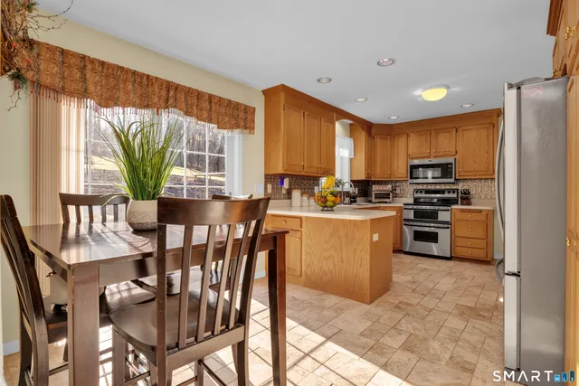 a kitchen with stainless steel appliances granite countertop a stove a refrigerator a kitchen island a table and chairs