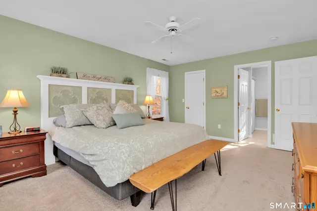 a spacious bedroom with a bed and a lamp on dresser