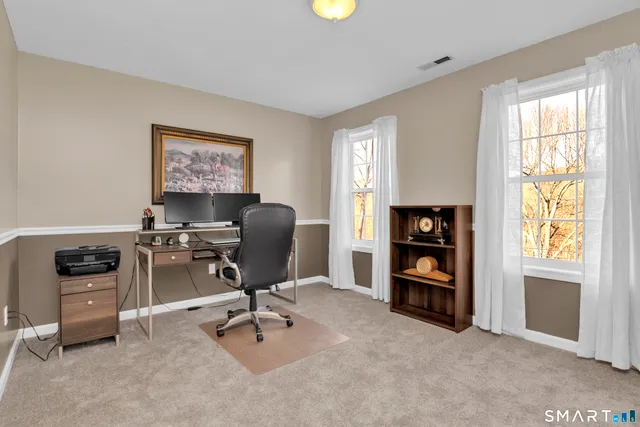 a view of a workspace with furniture and a window