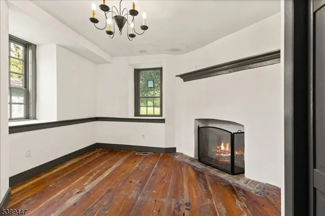 a view of empty room with a fireplace and wooden floor
