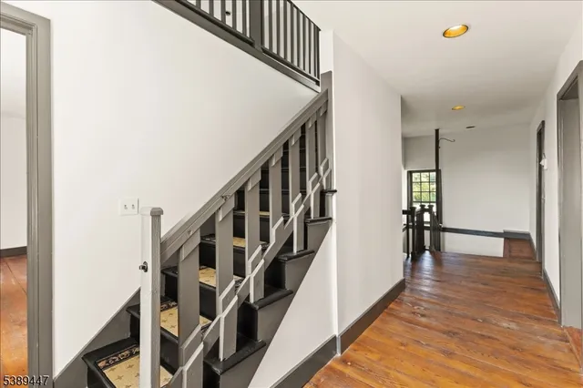 a view of staircase with wooden floor and white walls