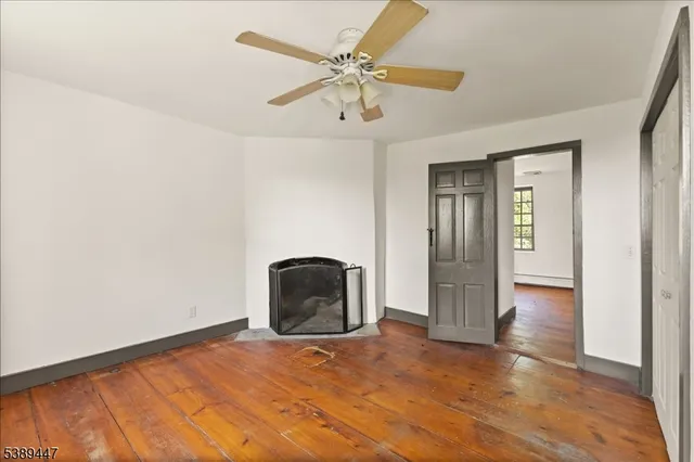 an empty room with wooden floor and ceiling fan