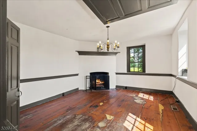 a view of an empty room with wooden floor fireplace and a window