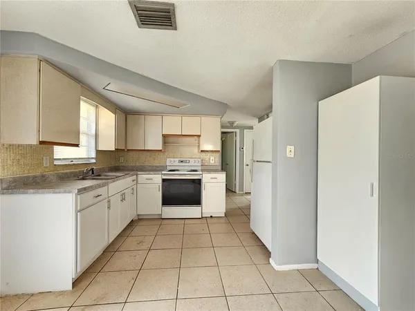 a large kitchen with a stove a refrigerator and a sink