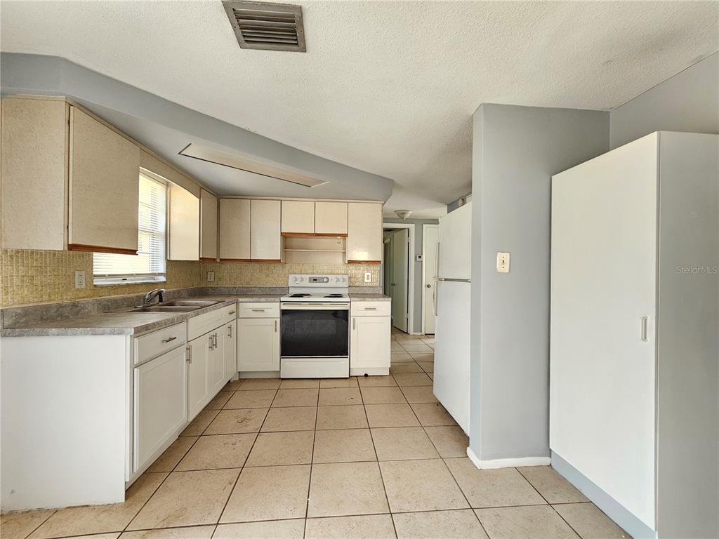 7825 Sagebrush Drive Port Richey, FL 34668 - Photo 8 of 17 a large kitchen with a stove a refrigerator and a sink