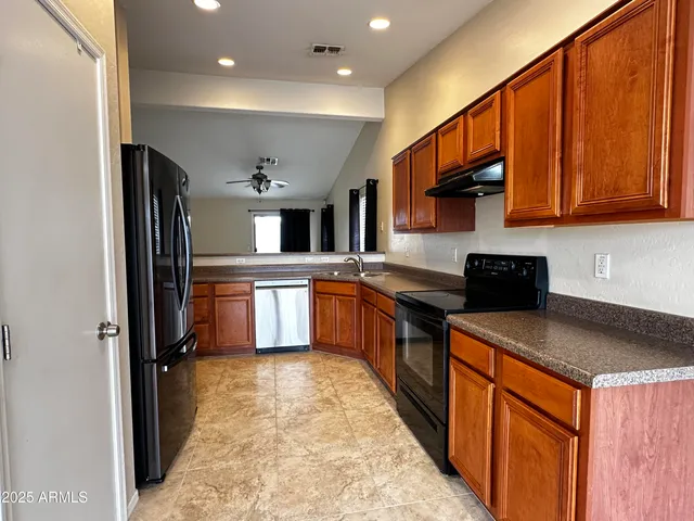 a kitchen with stainless steel appliances granite countertop a stove a sink dishwasher a refrigerator and cabinets with wooden floor
