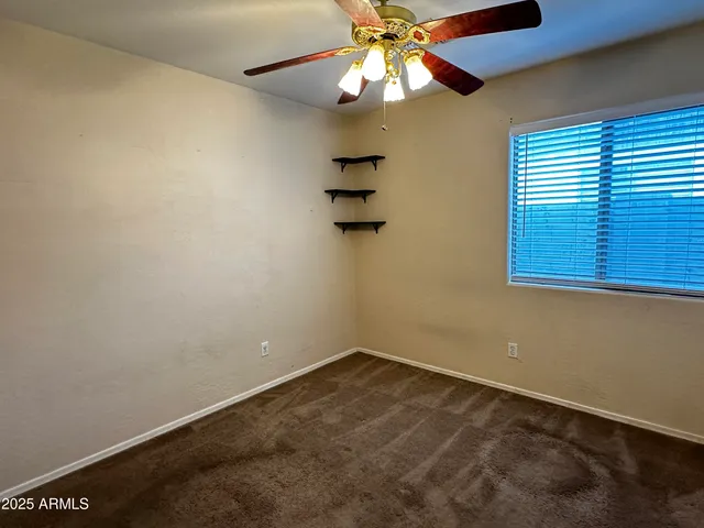 an empty room with a window and a ceiling fan