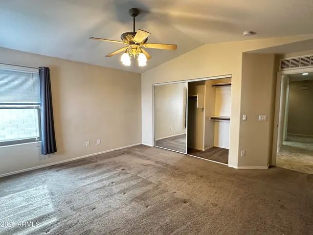 an empty room with chandelier fan and windows