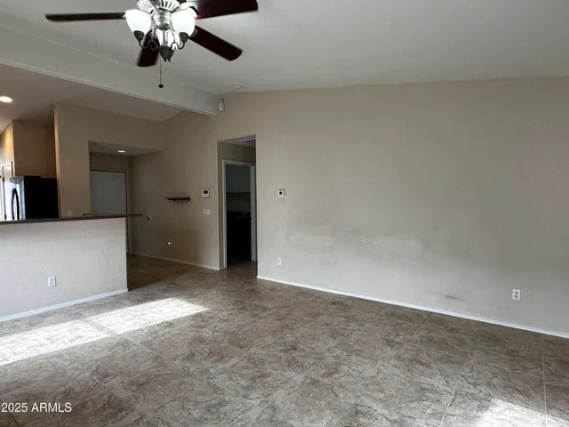 an empty room with a chandelier fan and windows