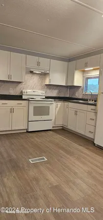 a kitchen with stainless steel appliances granite countertop a stove a sink and white cabinets