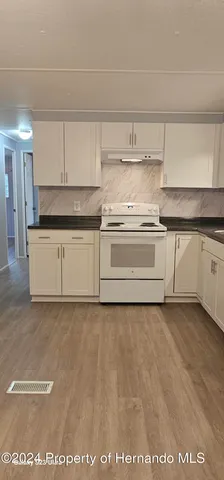 a kitchen with stainless steel appliances granite countertop a sink a stove a refrigerator a washer and dryer