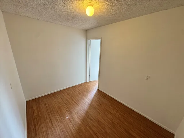 a view of an empty room with wooden floor and windows