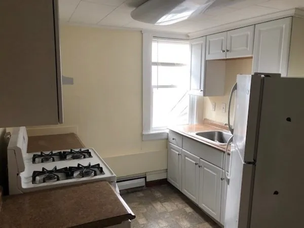 a kitchen with a stove a refrigerator and a window