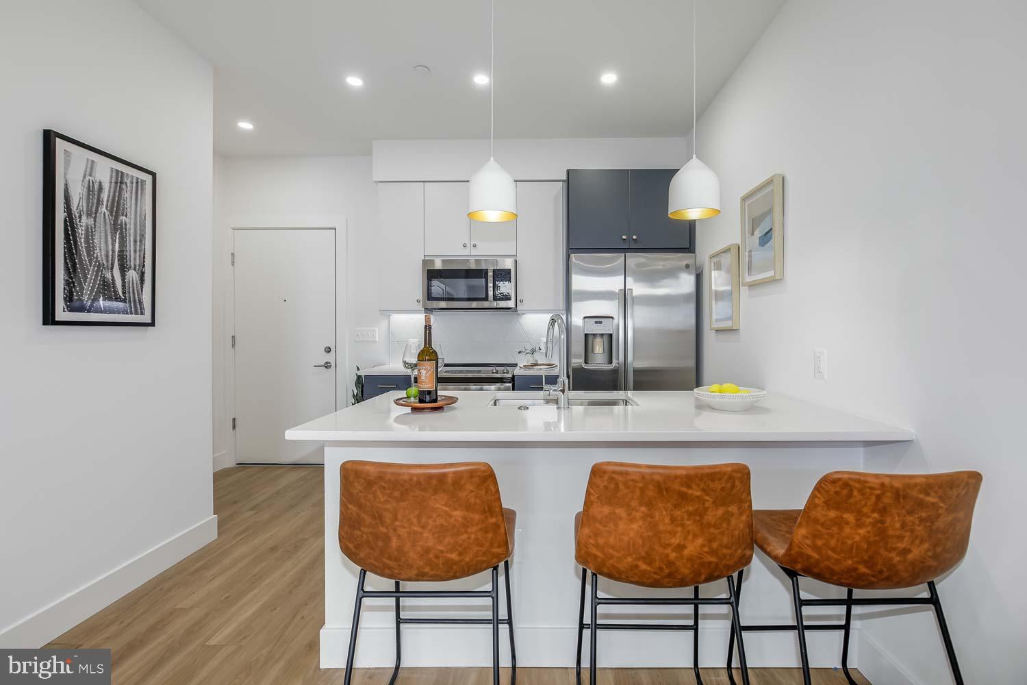 2310 4th Street Northeast, Unit 4TH 22 Washington, DC 20002 - Photo 4 of 18 a kitchen with stainless steel appliances granite countertop a table chairs sink and cabinets