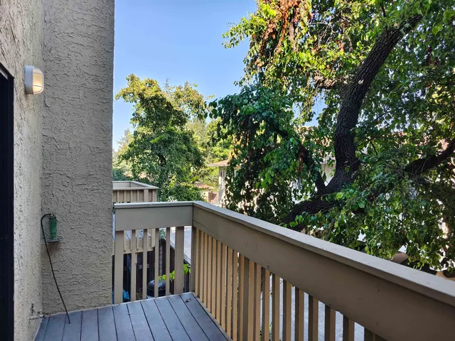 a balcony with wooden floor and yard in the back