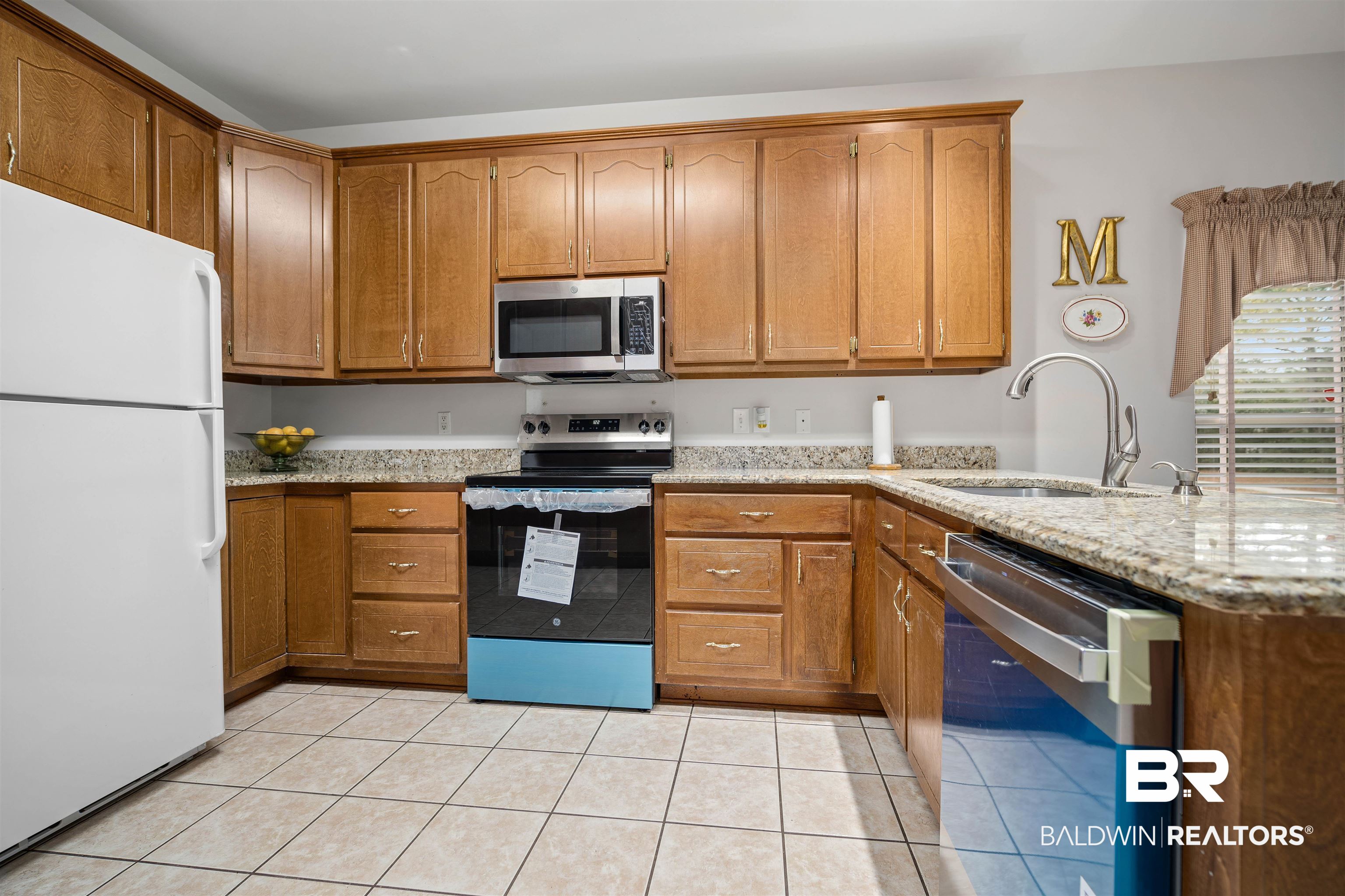 7419 Pake Road Saraland, AL 36571 - Photo 8 of 27 Kitchen featuring sink, light stone countertops, light tile patterned floors, kitchen peninsula, and stainless steel appliances