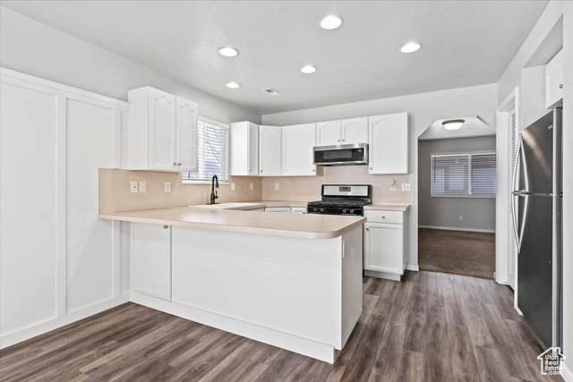 2421 North Washington Rd Boulevard, Unit I4 Ogden, UT 84414 - Photo 1 of 1 Kitchen with white cabinetry, appliances with stainless steel finishes, kitchen peninsula, dark hardwood / wood-style floors, and sink