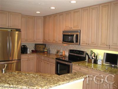 13002 Pennington Place, Unit 101 Fort Myers, FL 33913 - Photo 1 of 10 a kitchen with stainless steel appliances granite countertop a refrigerator stove top oven and sink