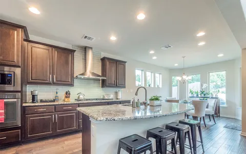 a kitchen with kitchen island granite countertop lots of counter top space and stainless steel appliances