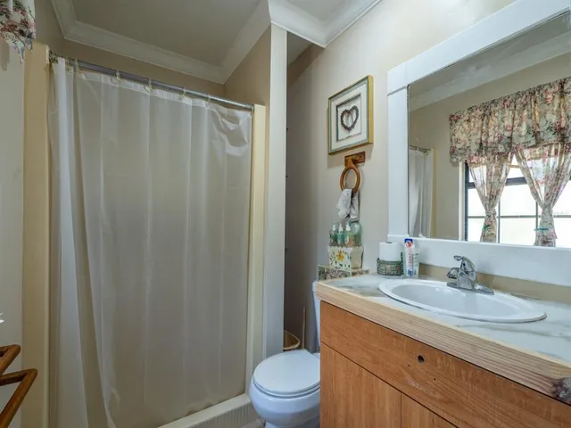 a bathroom with a granite countertop sink toilet a mirror a vanity and a shower