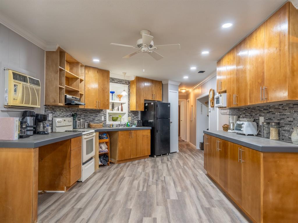 13455 Northeast 228 Ln Road Fort McCoy, FL 32134 - Photo 10 of 51 a kitchen with stainless steel appliances granite countertop a refrigerator a sink dishwasher a stove and a dining table with wooden floor