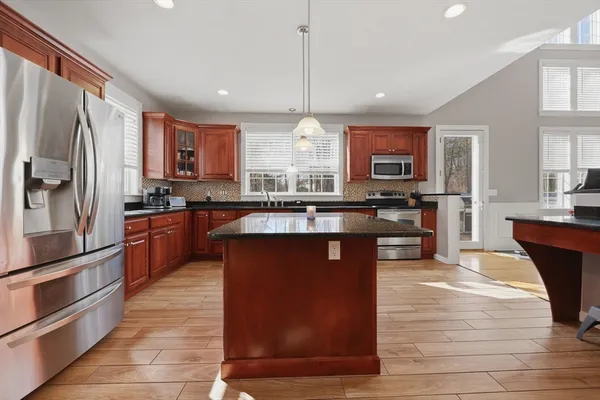 a kitchen with stainless steel appliances granite countertop a stove a sink dishwasher a refrigerator and a microwave oven with wooden floor