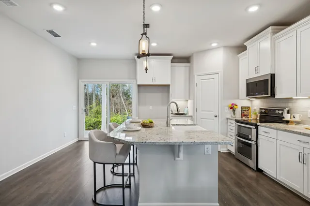 a kitchen with stainless steel appliances granite countertop a stove a sink dishwasher a microwave oven with a dining table and chairs