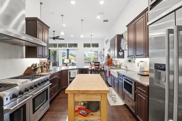 a kitchen with stainless steel appliances granite countertop a stove top oven a sink dishwasher a refrigerator and white cabinets with wooden floor