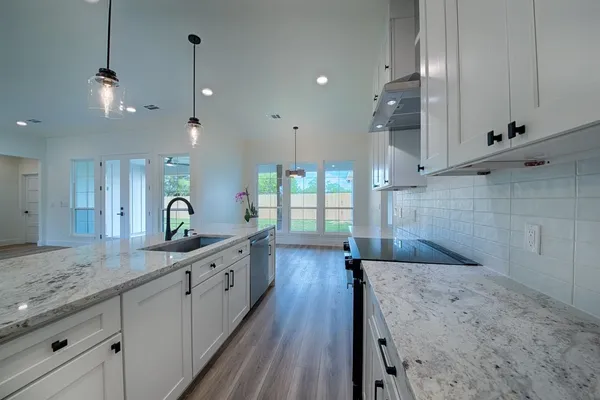 a large kitchen with kitchen island a stove a sink a center island and wooden floor