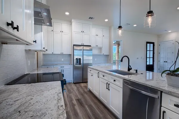 a large kitchen with stainless steel appliances granite countertop a sink a stove and a refrigerator