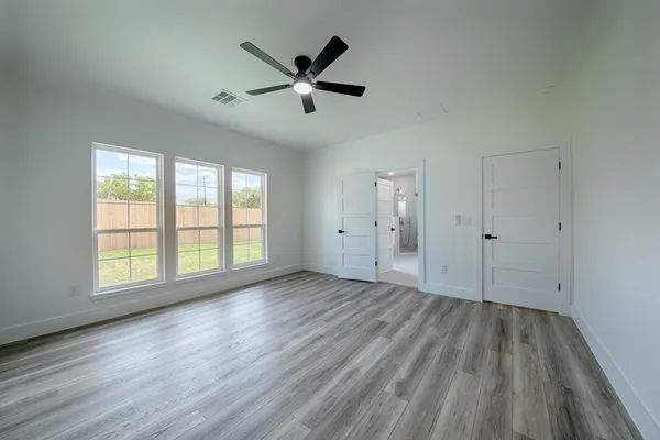 an empty room with wooden floor and windows