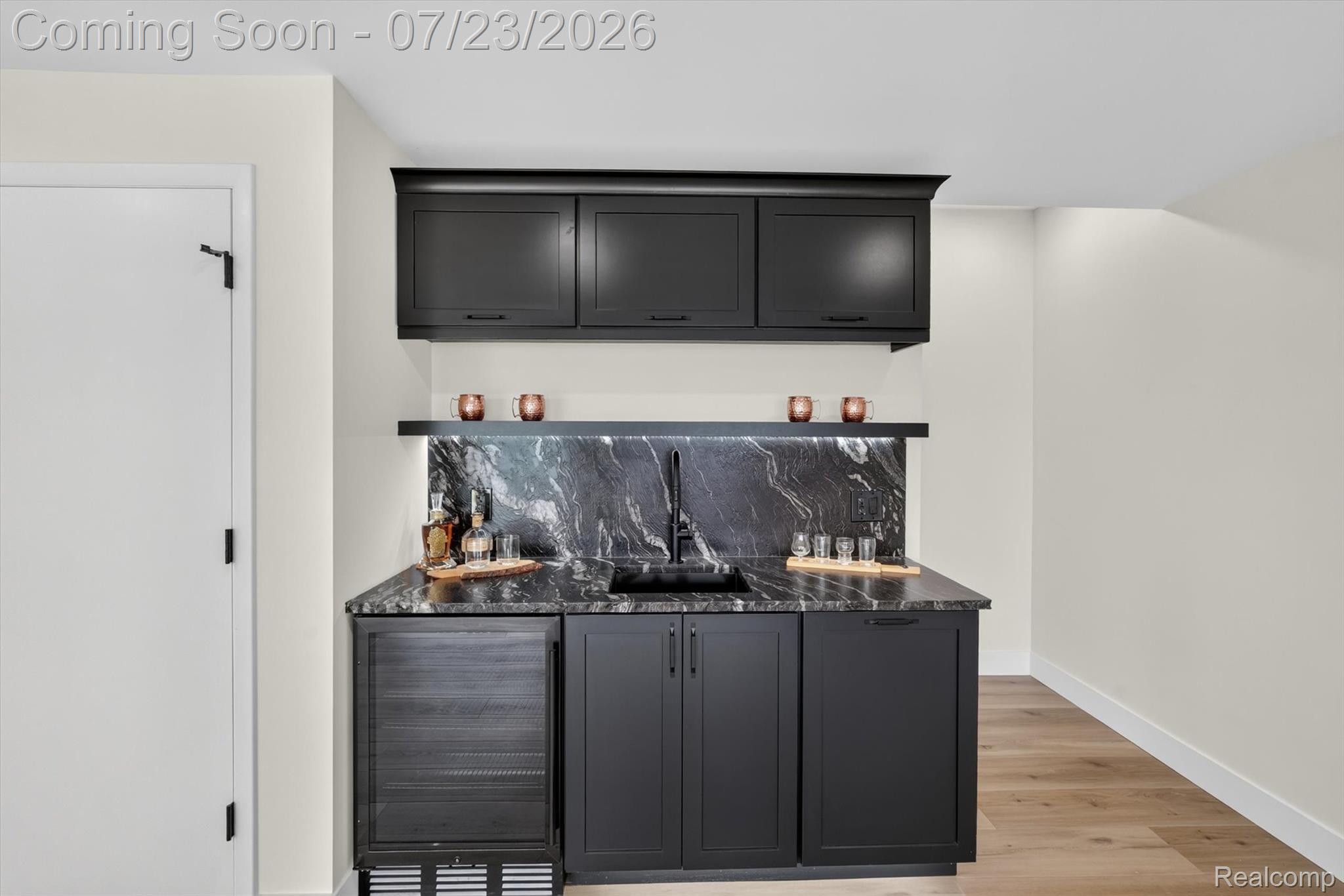 3429 Rolston Road Fenton, MI 48430 - Photo 38 of 62 Wet bar featuring dark cabinetry, stone countertops, stone backsplash, integrated beverage refrigerator, and wood-finish flooring