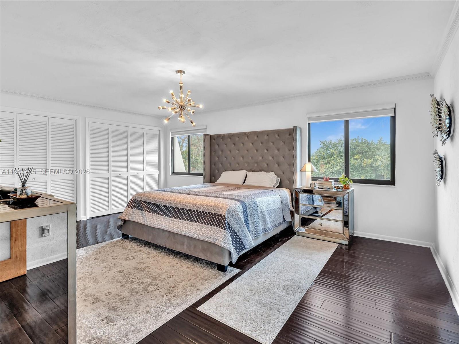 7661 Southwest 102nd Place Miami, FL 33173 - Photo 16 of 51 a bedroom with a large bed a chandelier and windows