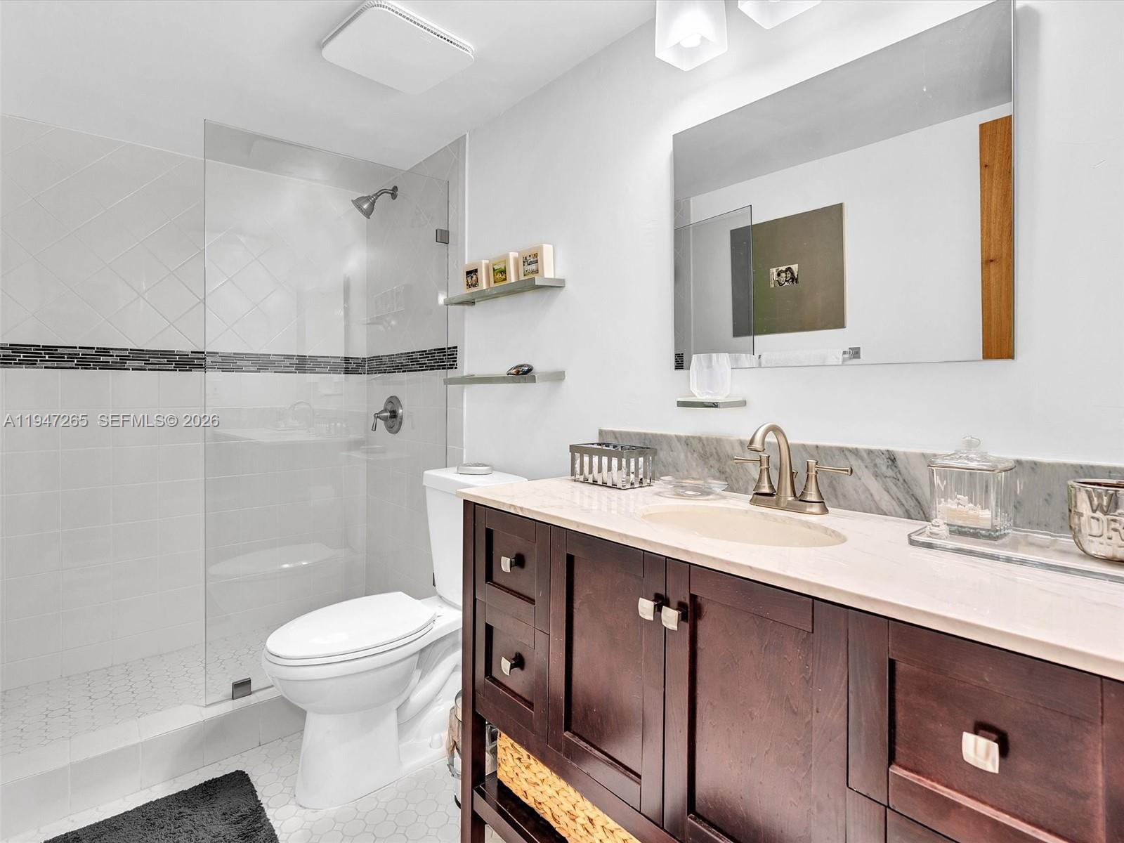7661 Southwest 102nd Place Miami, FL 33173 - Photo 24 of 51 a bathroom with a granite countertop toilet sink and mirror