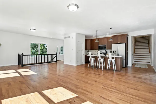 a dining hall with stainless steel appliances a dining table wooden floor a fireplace and a window