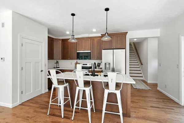 a kitchen with stainless steel appliances kitchen island granite countertop a dining table chairs and white cabinets