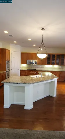 a kitchen with stainless steel appliances granite countertop a sink and a wooden floor
