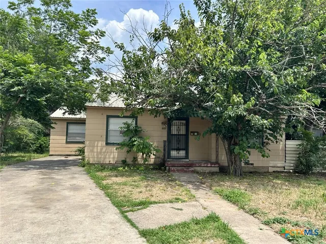 a front view of house with yard and trees in the background