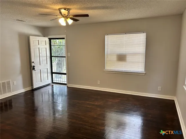a view of an empty room with wooden floor and a window