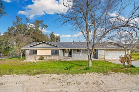 a front view of a house with a garden and trees