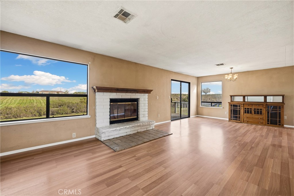 6980 Cabernet Place Paso Robles, CA 93446 - Photo 6 of 30 an empty room with wooden floor fireplace and windows