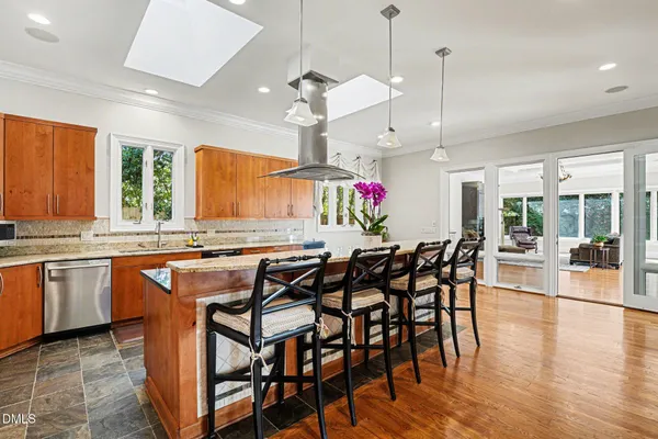 a kitchen with stainless steel appliances granite countertop table chairs and wooden cabinets