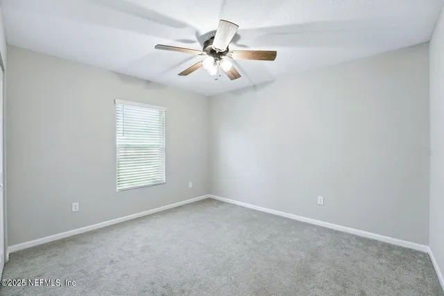 an empty room with windows and fan